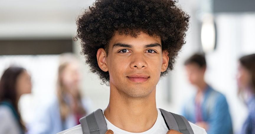 a young person with dark hair wearing a white t-shirt and carrying a backpack