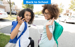 Two young people with backpacks smile and wave